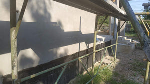 Applying Adhesive and Spackle to a House with a Metal Structure on the Ground Floor thumbnail